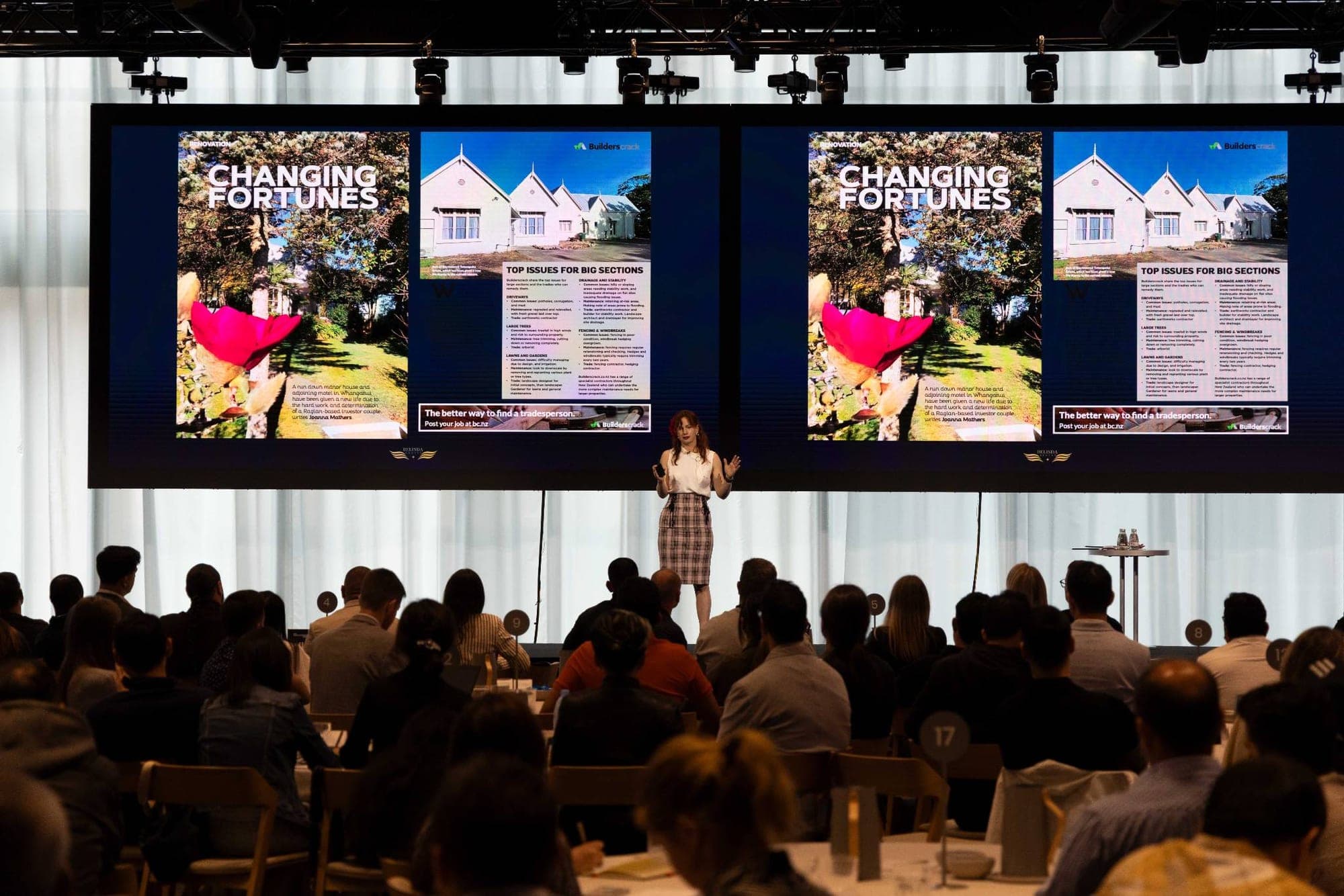 Belinda Beatty on stage teaching a room, property renovation case study on the screens behind her