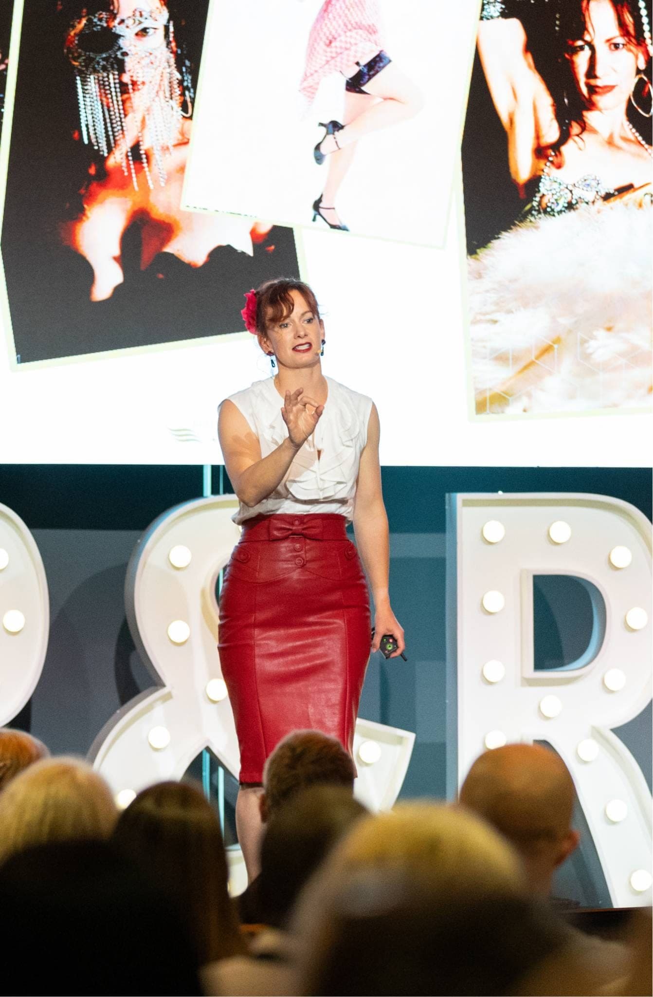 Belinda Beatty delivering a keynote, her performance photographs projected on the screen behind her